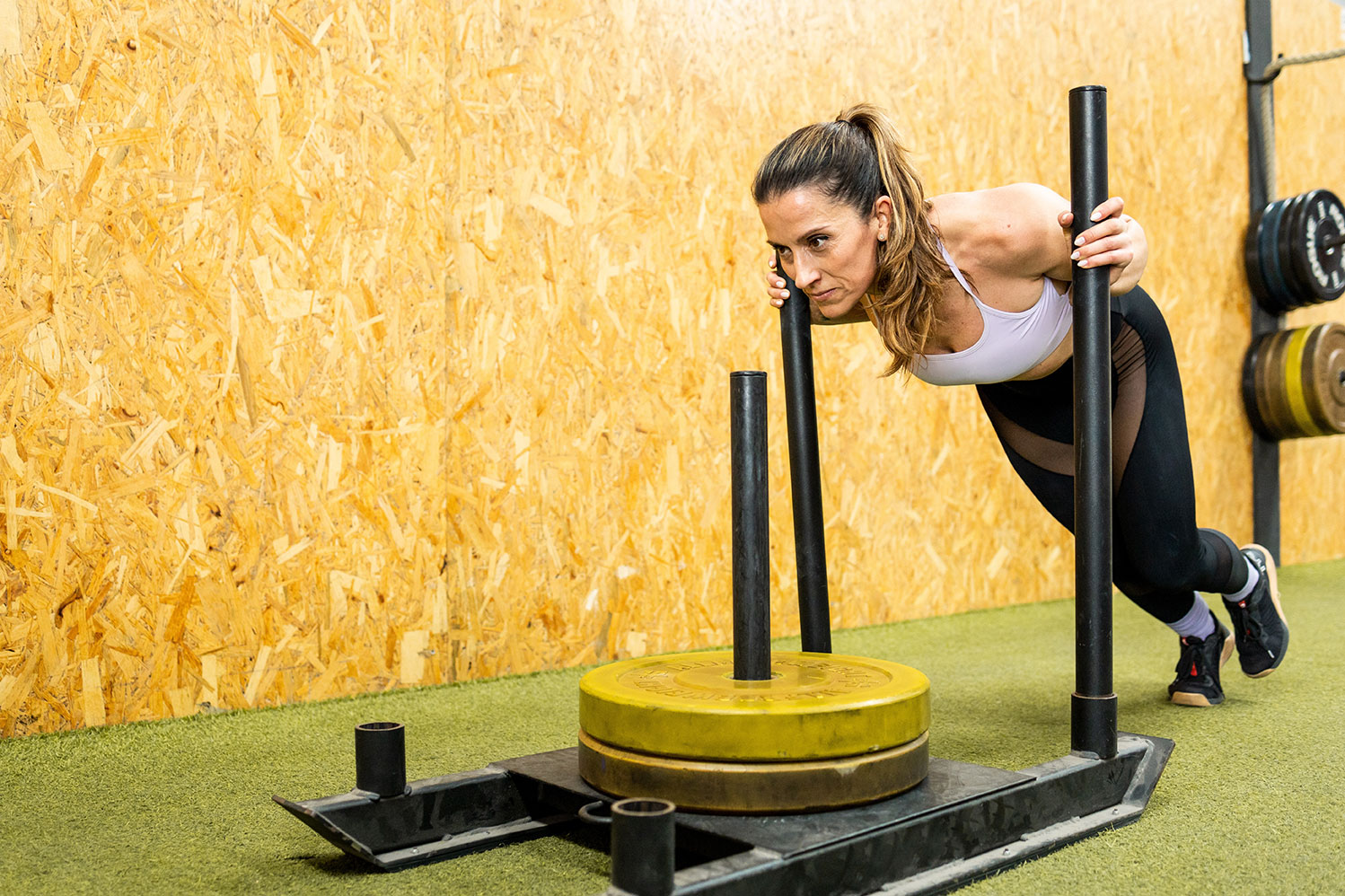 alimentazione hyrox sport di fitness inventato in Germania. Foto con atleta femmina svolgendo esercizio sled push