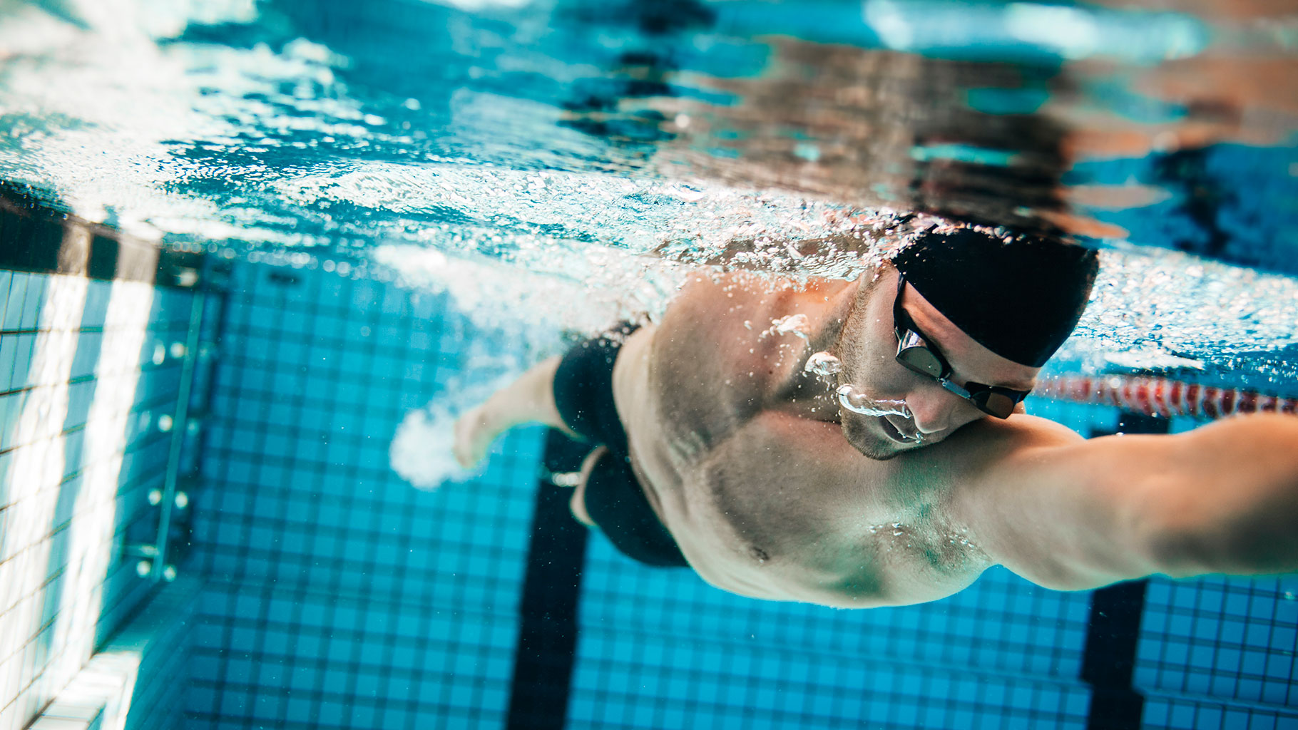nutrizionista nuoto agonistico, foto con nuotatore professionista immerso nell'acqua di una piscina olimpionica